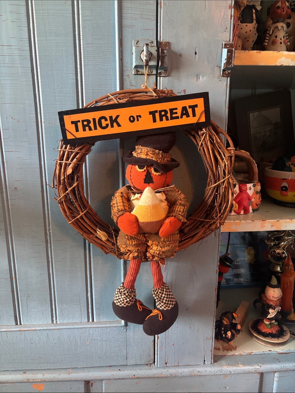 Halloween wreath with fabric jack-o’-lantern figurine, holding up candy corn